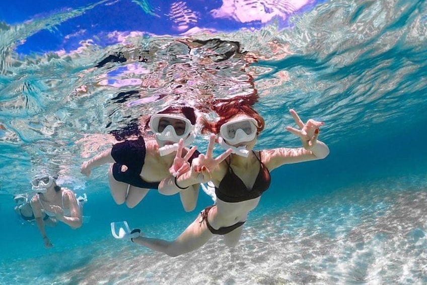 Two people snorkeling underwater with clear water and rocky formations. 5
