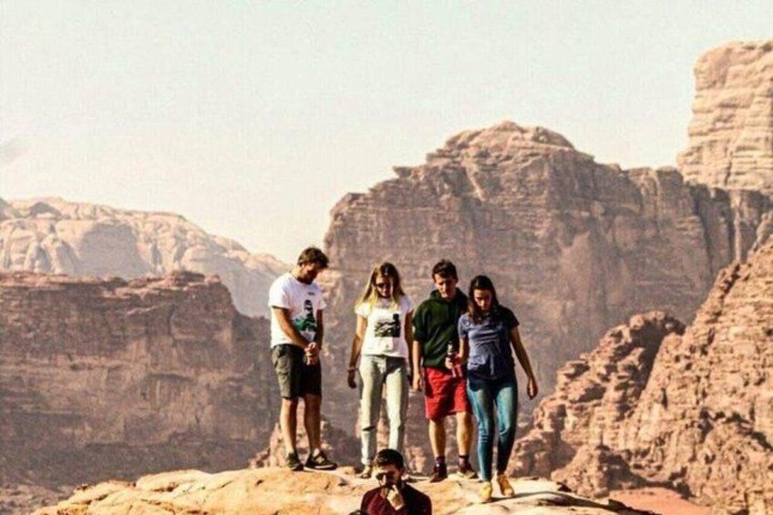 Un groupe de personnes se tient sur un promontoire rocheux, avec un paysage désertique en arrière-plan. 3