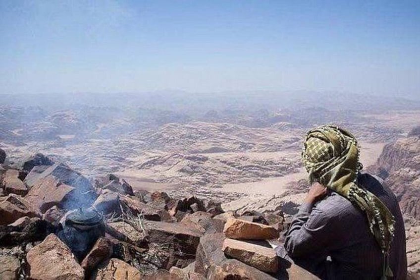 Une personne assise sur un promontoire rocheux, d’où elle domine un vaste paysage désertique. 4