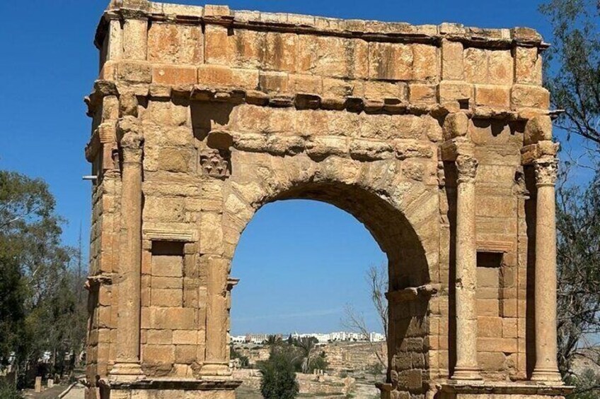 An ancient stone archway with intricate carvings, set against a clear blue sky. 4