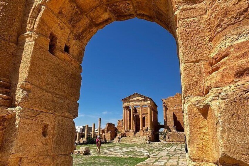 An ancient stone archway framing a classical building with columns. 3