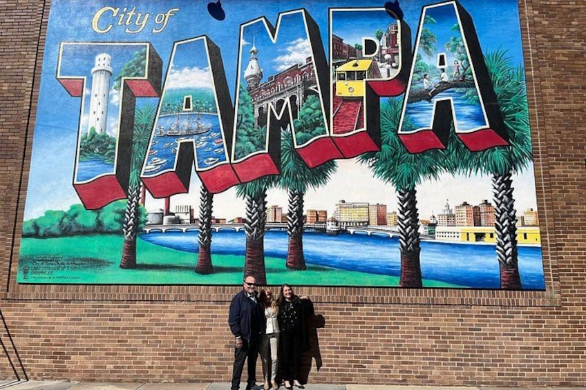 A mural of the City of Tampa with palm trees, a lighthouse, and a river. 2