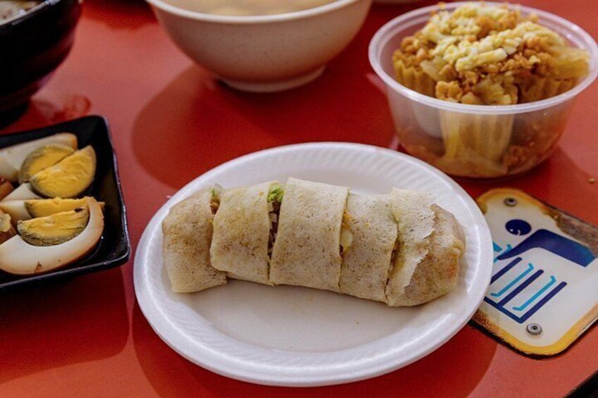 Un plato con un alimento enrollado, un tazón y un recipiente con una mezcla de frutos secos. 3