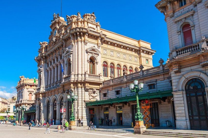 Un edificio histórico con arquitectura ornamentada, un toldo verde y una calle con gente caminando. 2