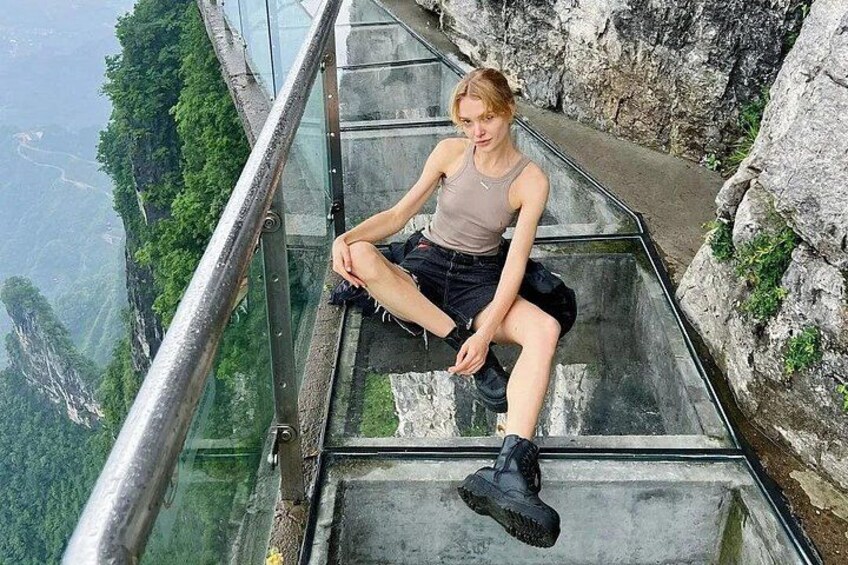 A person sitting on glass stairs overlooking a mountainous landscape. 1