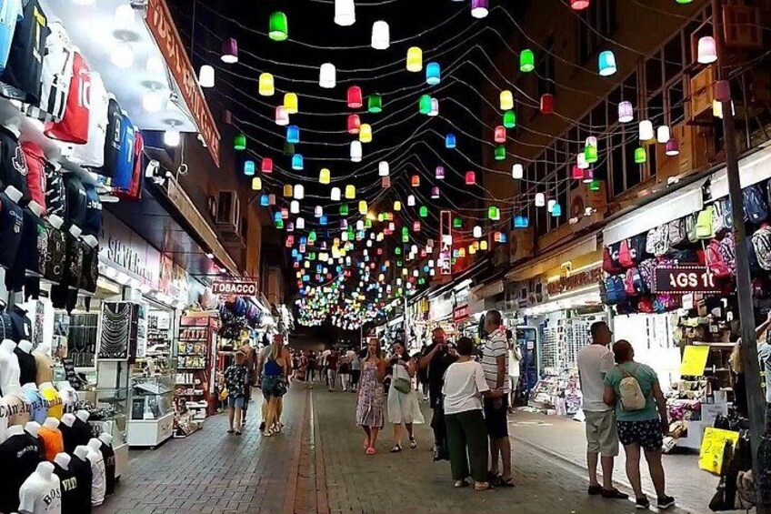 Un mercato al chiuso vivace, con lanterne colorate appese, diversi negozi e persone che curiosano. 3