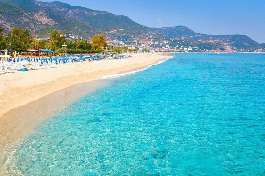 Una spiaggia con acque cristalline turchesi, una riva sabbiosa e montagne sullo sfondo. 2