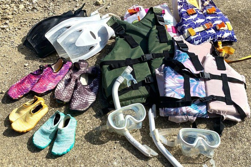 A collection of diving gear, including fins, snorkels, and a diving mask, laid out on the ground. 3