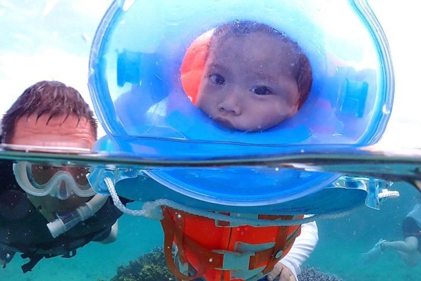 A person in a diving mask with a child inside, underwater. 3