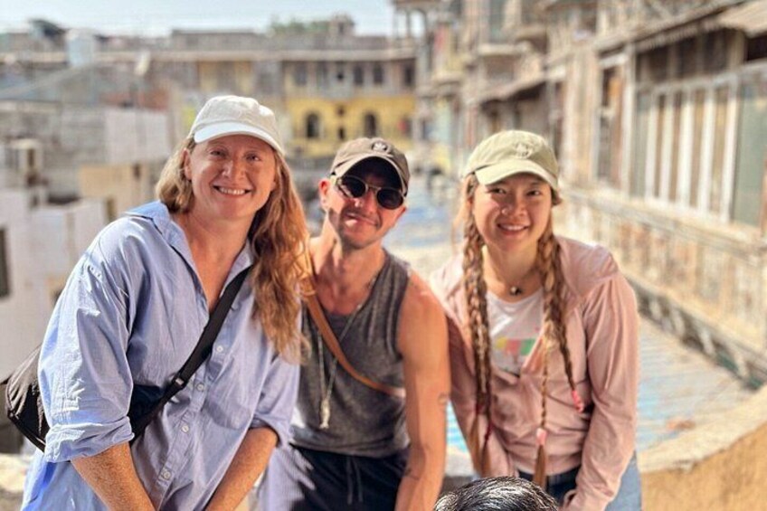 Three people standing on a bridge with buildings in the background. 5