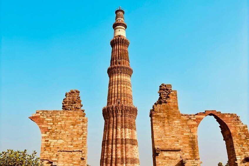 A tall, slender minaret with intricate carvings, surrounded by ancient brick ruins. 4