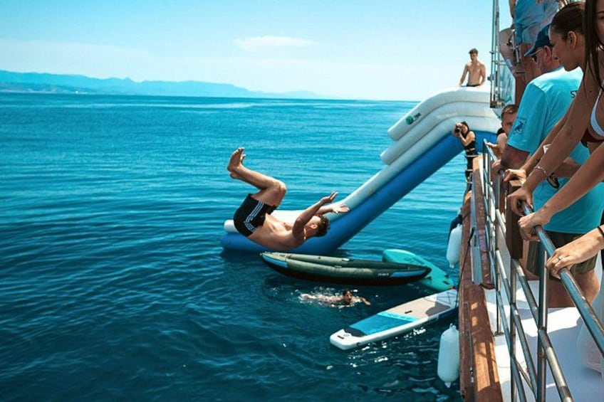 A person lying on a surfboard in the water, another person on a stand-up paddleboard, and a group of people on a boat. 3