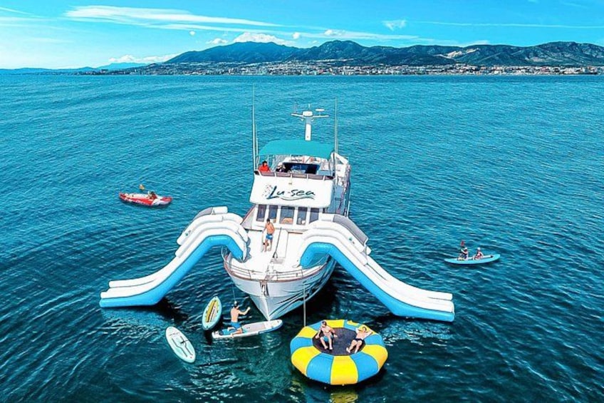 A water park with a large slide, inflatable rings, and a boat in the background. 1