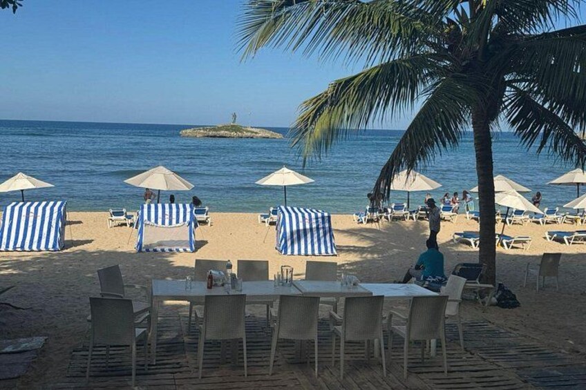 A beach with striped umbrellas, lounge chairs, and a palm tree. 4