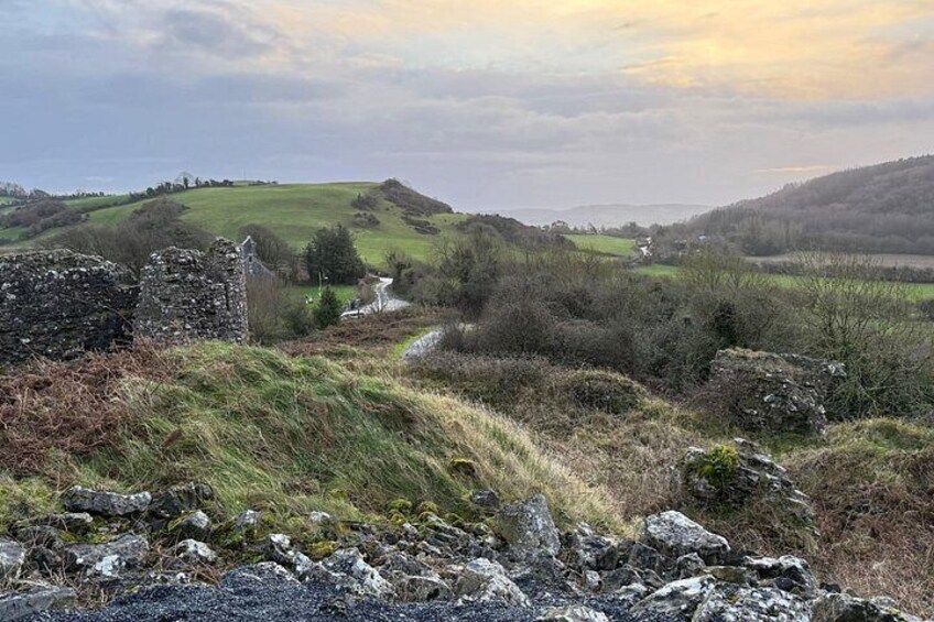 A rural landscape with rolling hills, a stone structure, and a narrow path. 2
