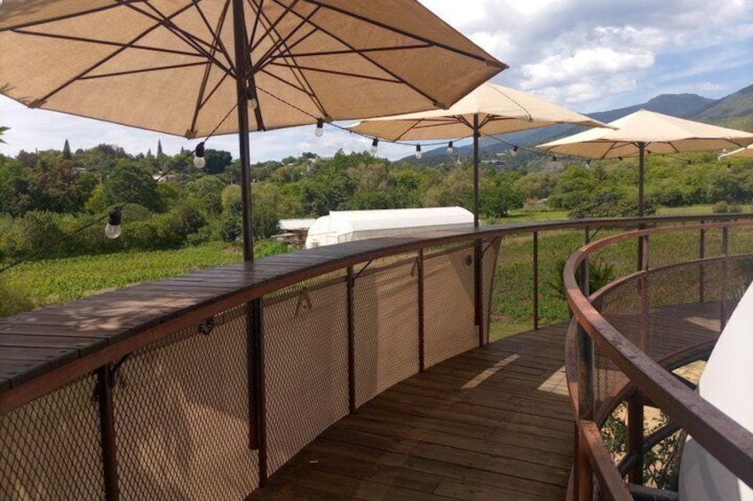 A wooden deck with outdoor umbrellas, a grill, and a scenic view of greenery and mountains. 5