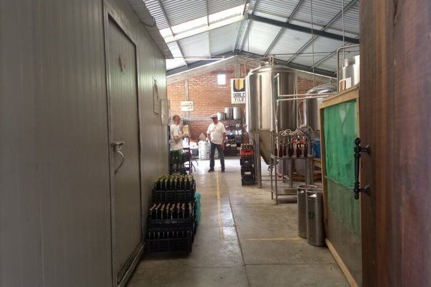 A brewery interior with stainless steel tanks, crates of beer, and a brick wall in the background. 4