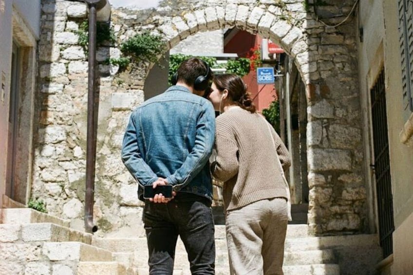 A couple walking down a stone staircase in a narrow alleyway with a sign above them. 3