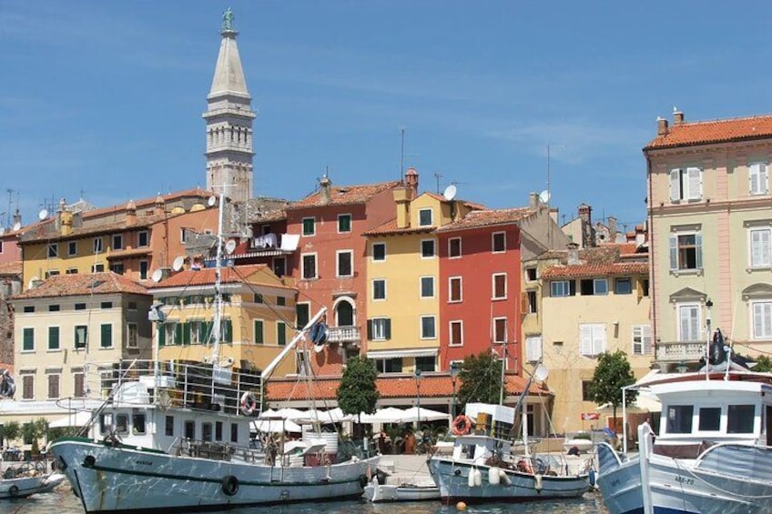 A coastal town with colorful buildings, a prominent tower, and boats docked at the marina. 2