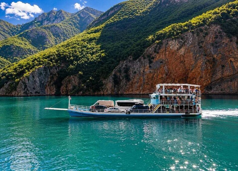 A boat with passengers on a turquoise lake surrounded by mountains. 1