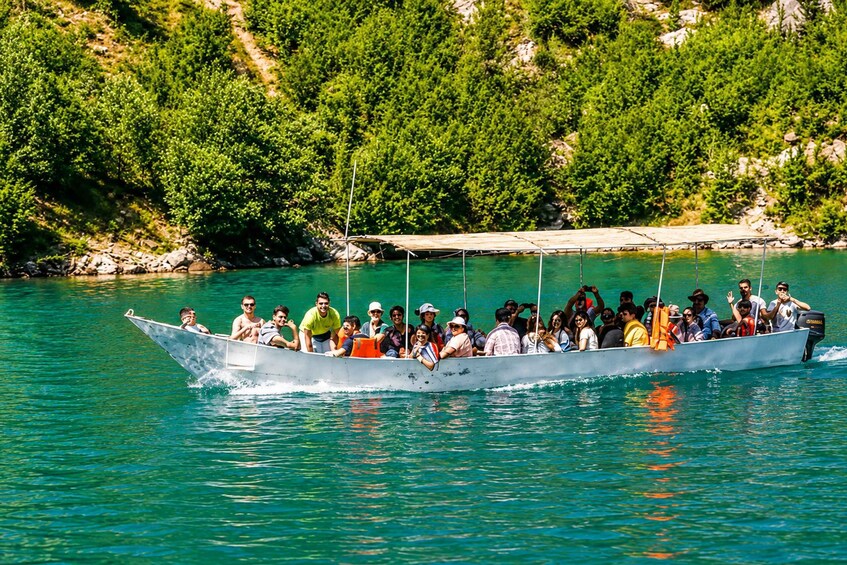 A boat filled with people on a calm body of water surrounded by greenery. 5