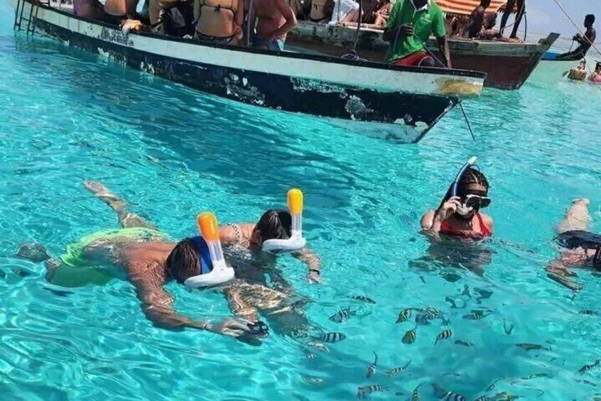 Folk svømmer i en pool med både i baggrunden. 5