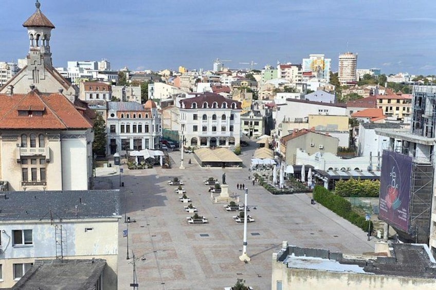 A cityscape with a prominent church, a large open square, and a view of the sea. 2
