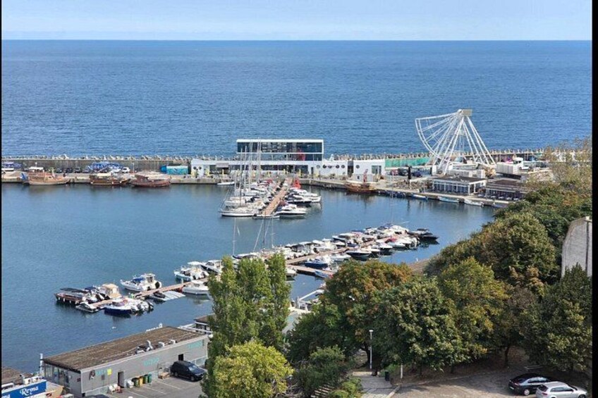 A marina with boats, a Ferris wheel, and a building with a modern design. 5