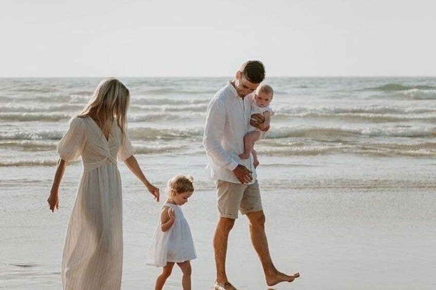 A family walking on a beach with the ocean in the background. 4