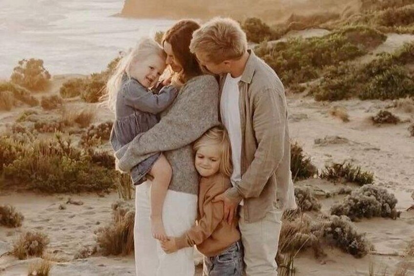 A family on a beach with sand dunes and ocean in the background. 3