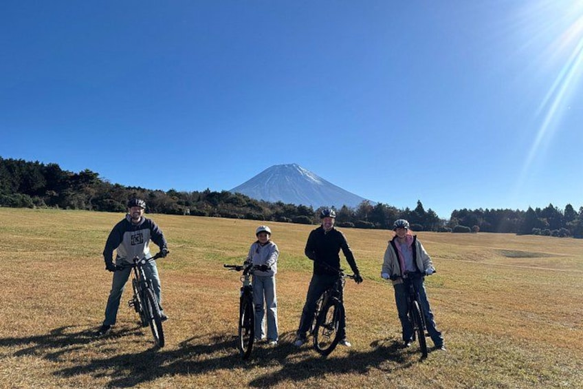 Four people on bicycles in a field with a mountain in the background. 1