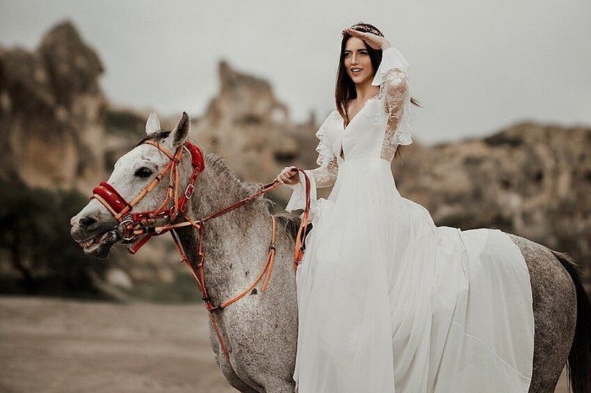 A person in a white dress riding a horse with a red bridle. 5