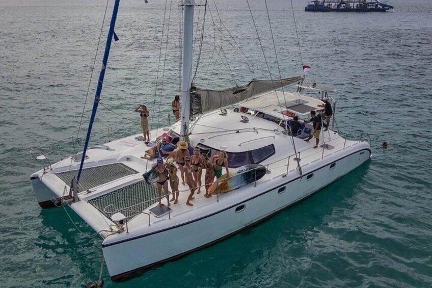 Een witte zeilboot met mensen op het dek, kalme zee en een ander schip op de achtergrond. 3