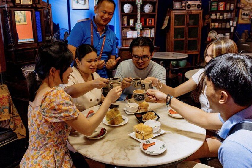 Een groep mensen proost met bekers rond een tafel met eten en drinken. 2