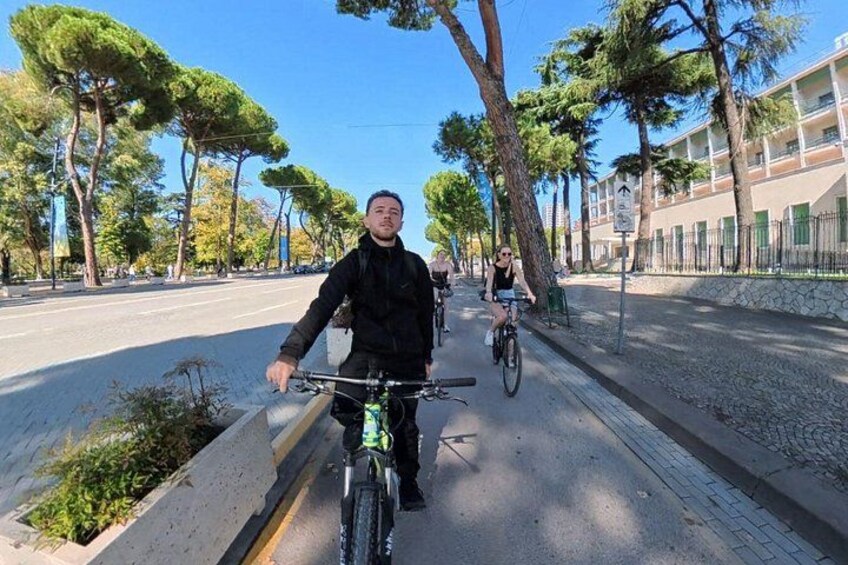 Una persona en bicicleta por una calle arbolada. 5