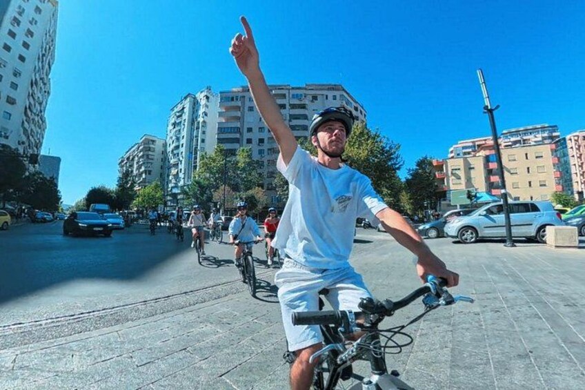 Una persona montando en bicicleta por una calle urbana con edificios al fondo. 3