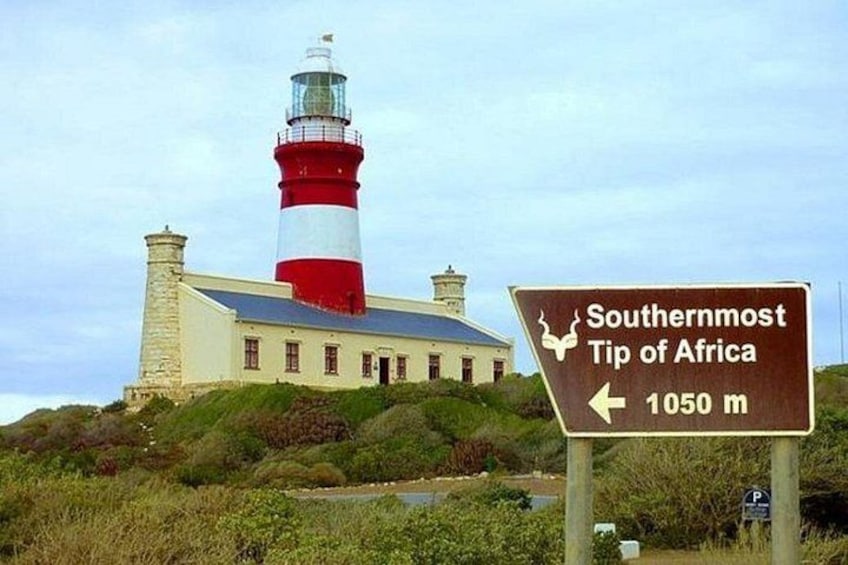 Een vuurtoren, een bord met 'Zuiderpunt van Afrika' en een afstandsaanduiding van 1050 meter. 1