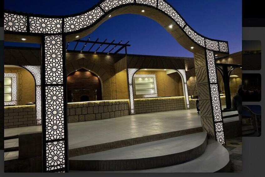 An outdoor patio area with a stone floor, arched structures, and decorative lattice panels. 5