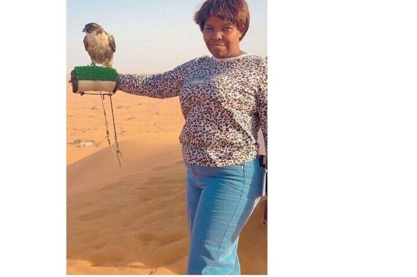 A person holding a bird on a stick in a desert. 3
