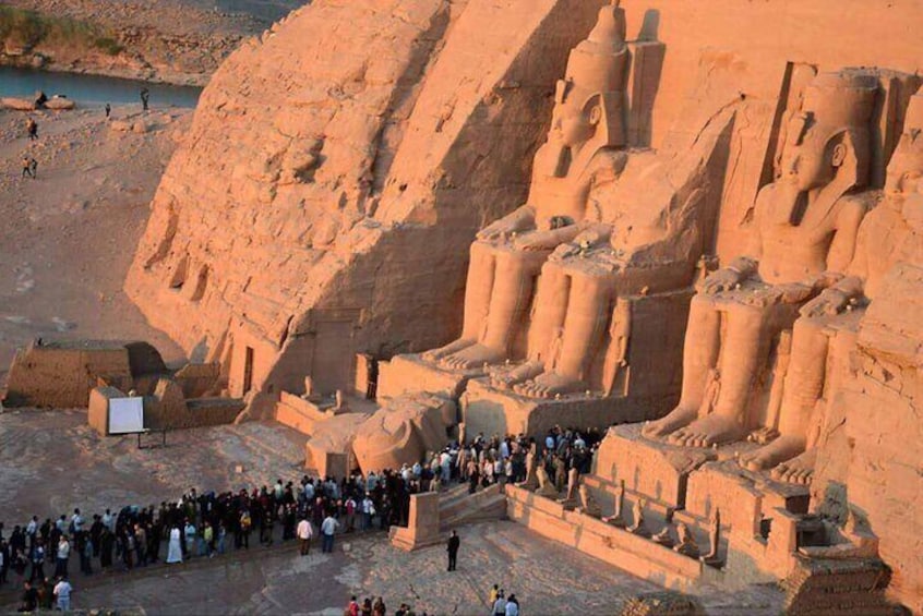A large group of people gathered around ancient Egyptian statues and ruins. 5