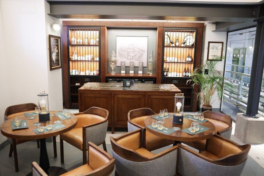 En restaurant med runde borde og stole, et barområde med hylder af flasker, og et stort vindue med udsigt. 2