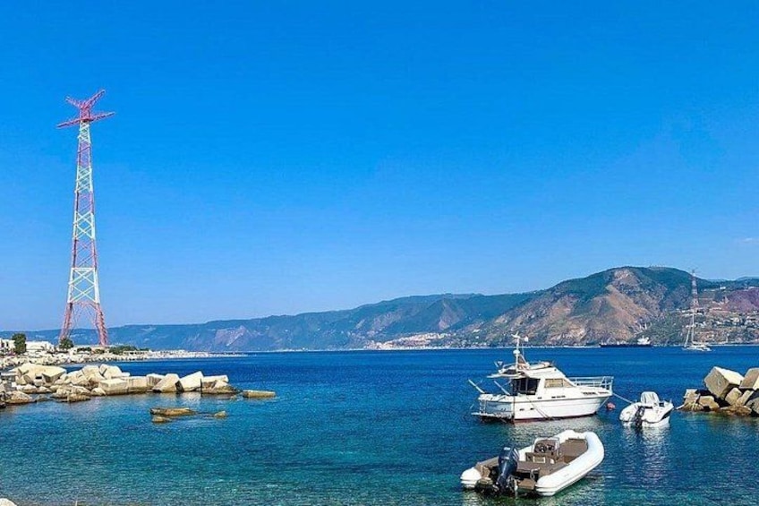 A coastal scene with a transmission tower, boats, and a mountainous landscape. 2
