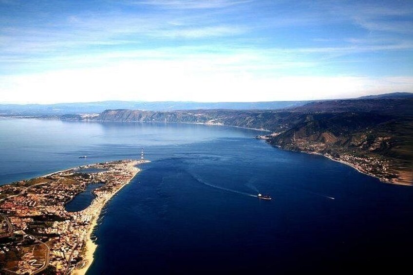 A coastal city with a lighthouse, a large body of water, and a hilly landscape. 4