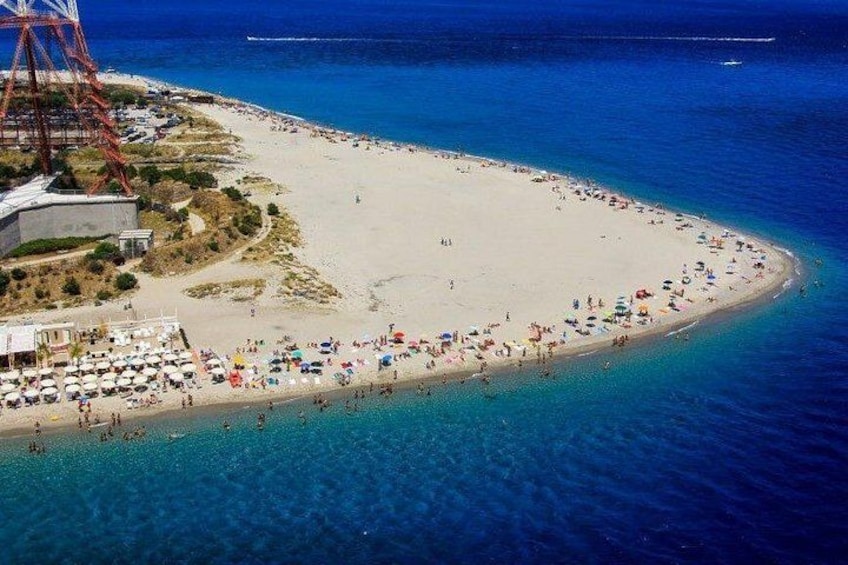 A beach with clear blue water, a sandy shore, and a few umbrellas. 3