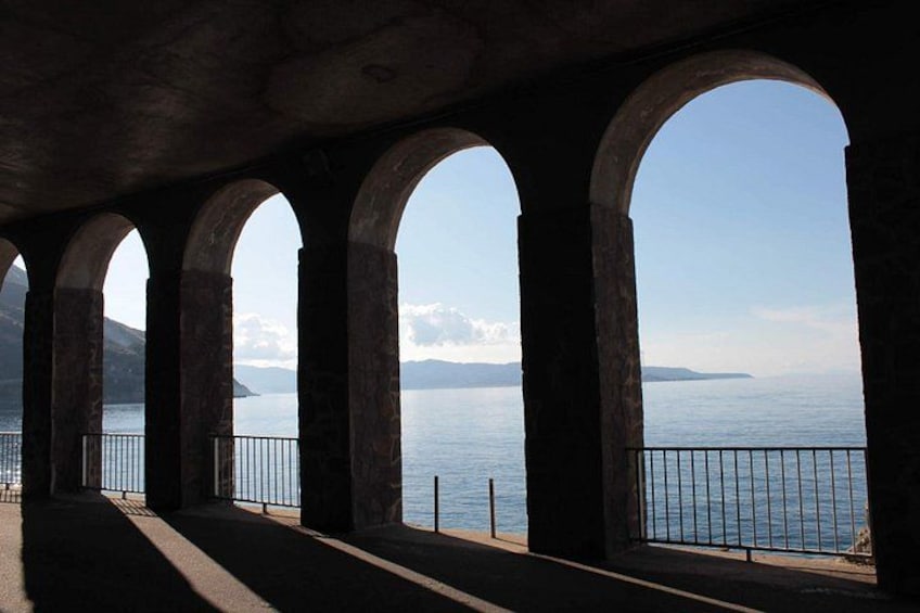 A series of arches overlooking a calm body of water with distant landforms. 5