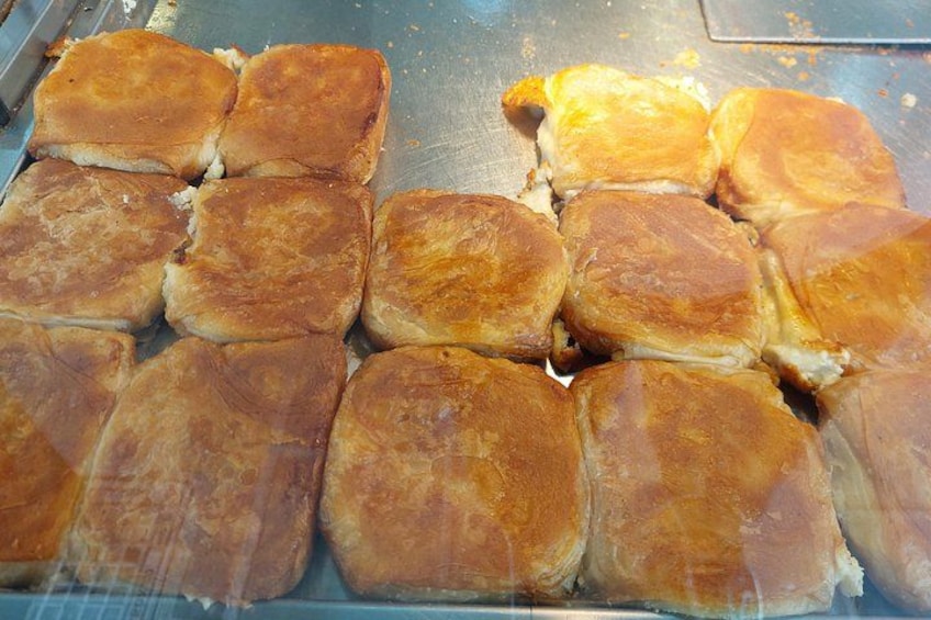 Une plaque de pâtisseries dorées et cuites au four, peut-être du pain ou des viennoiseries, disposées en rangées. 4