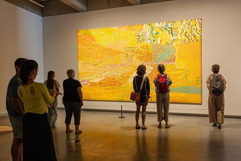A group of people observing a large abstract painting in an art gallery. 4
