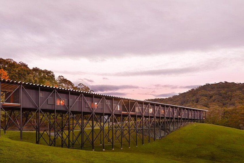 A bridge with a metal framework and a covered walkway, surrounded by green hills and trees. 3