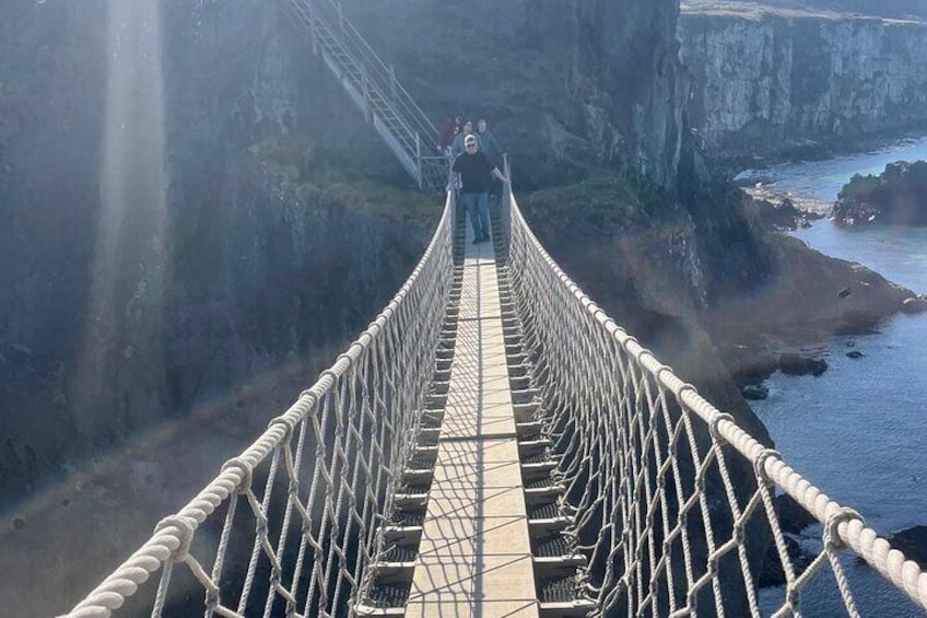 Eine Seilbrücke über einer Klippe, am Ende steht eine Person. 4