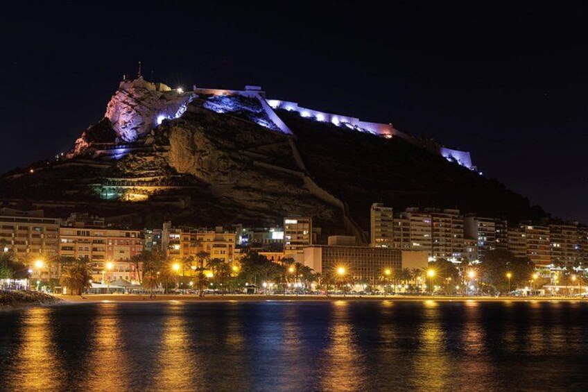 A cityscape at night with illuminated buildings and a prominent hill with lights. 5